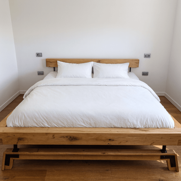 Wooden bed frame with a white comforter and two pillows on a wooden floor.